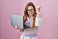 Young caucasian woman working using computer laptop angry and mad raising fist frustrated and furious while shouting with anger Royalty Free Stock Photo