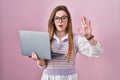 Young caucasian woman working using computer laptop doing stop gesture with hands palms, angry and frustration expression Royalty Free Stock Photo