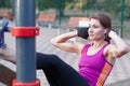 Young caucasian woman workouts on the park sports ground. The girl does abdominal excersise, in black and lilac sportswear. White Royalty Free Stock Photo