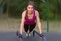 Young caucasian woman workouts on the park sports ground, in a plank position, bright sportswear.