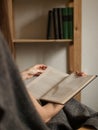 Detail view on book in hands with bookcase in background Royalty Free Stock Photo