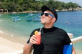 Young caucausian man enjoys coctail at ocean resort during summ