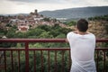 Young Caucausian man in a short white T-shirt leaning on the bar of a bridge.