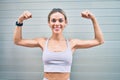 Young cauciasian fitness woman wearing sport clothes training outdoors with raised arms showing muscle proud