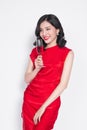 Young celebrating asian woman in red dress holding wine glass.