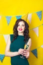 Young celebrating woman green dress, holding a glass of champagne.