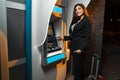 Young charismatic businesswoman posing in front of ATM