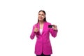 young charismatic successful brunette business lady dressed in a bright crimson jacket holds a plastic credit card on a
