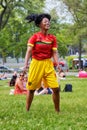 Young and charming Afro American female with a red jersey and yellow shorts dancing on the grass of Mount Royal Park
