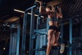 Young charming blonde woman in sportswear does pull-ups on a graviton machine in the modern fitness center.