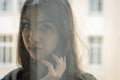 Young charming brunette girl behind a glass window Royalty Free Stock Photo