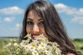 Young charming brunette girl with a bouquet of white field chamomiles on a summer sunny day