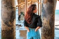 A young charming brunette woman in a black shirt and denim shorts poses under a pier on the beach of Malibu, California Royalty Free Stock Photo