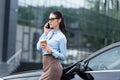 Young charming businesswoman talking on smartphone and holding a cup Royalty Free Stock Photo