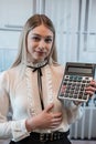 Young charming caucasian woman in suit hold calculator in business cetner