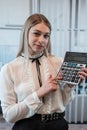 Young charming caucasian woman in suit hold calculator in business cetner