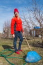 Young charming female gardener stands in her garden on blue sky background, closeup garden tools, vertical picture