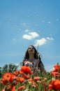 A young charming girl in a chamomile poppy field throws flowers of daisies on a bright sunny day