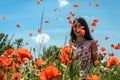 Young charming girl in a chamomile poppy field tosses petals of poppies on a bright sunny day