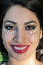 Young charming girl doing eye make-up using petals of chamomile flowers