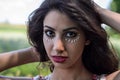 Young charming girl doing eye make-up using petals of chamomile flowers