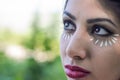 Young charming girl doing eye make-up using petals of chamomile flowers