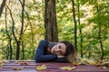 Young charming girl with long hair is lying on the table among the fallen yellow leaves in the autumn park Royalty Free Stock Photo