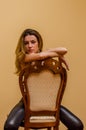 Young charming girl with long hair sits on a vintage classic wooden chair isolated on a light background Royalty Free Stock Photo