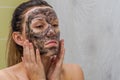 Young charming girl makes a black charcoal mask on her face Royalty Free Stock Photo