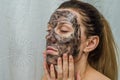 Young charming girl makes a black charcoal mask on her face Royalty Free Stock Photo