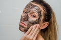 Young charming girl makes a black charcoal mask on her face Royalty Free Stock Photo