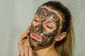 Young charming girl makes a black charcoal mask on her face Royalty Free Stock Photo