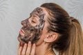 Young charming girl makes a black charcoal mask on her face Royalty Free Stock Photo