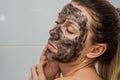 Young charming girl makes a black charcoal mask on her face Royalty Free Stock Photo