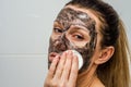 Young charming girl makes a black charcoal mask on her face Royalty Free Stock Photo