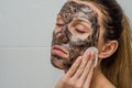 Young charming girl makes a black charcoal mask on her face Royalty Free Stock Photo