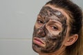 Young charming girl makes a black charcoal mask on her face Royalty Free Stock Photo