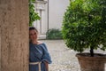 Young charming girl stands in the antique courtyard during the rain