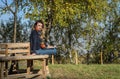 Young charming girl student sits on a bench in the autumn forest and reads a book Royalty Free Stock Photo