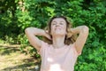 Young charming girl in summer park happy plays with hair