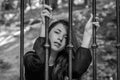 Young charming girl the teenager with long hair sitting behind bars in prison prisoner in a medieval jail with sad, pleading eyes Royalty Free Stock Photo