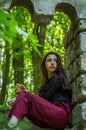 Young charming girl the teenager with long hair sitting on the sad ruins of an ancient stone castle window in Striysky Park in Lvi Royalty Free Stock Photo