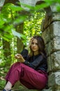 Young charming girl the teenager with long hair sitting on the sad ruins of an ancient stone castle window in Striysky Park in Lvi Royalty Free Stock Photo