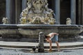 Young charming girl tourist drinks water from an antique drinking fountain of the roman nose against the background of historical Royalty Free Stock Photo