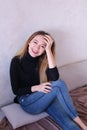 Young charming girl wearing black blouse sitting near wall.