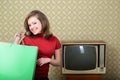 Young charming happy smiling woman holds shopping bags in room with vintage wallpaper and retro TV set, retro stylization 60-70s.