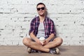 Young charming hipster sitting against the wall Royalty Free Stock Photo