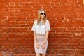 Young charming hipster woman in a white vintage lace blouse in black sunglasses with a luxurious necklace in an elegant skirt