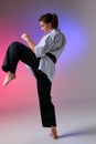 Athletic woman in traditional kimono is practicing karate in studio.