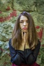 Young charming teenager girl with long dark hair standing near the ruins of the ancient castle fortress with a sad expression on Royalty Free Stock Photo